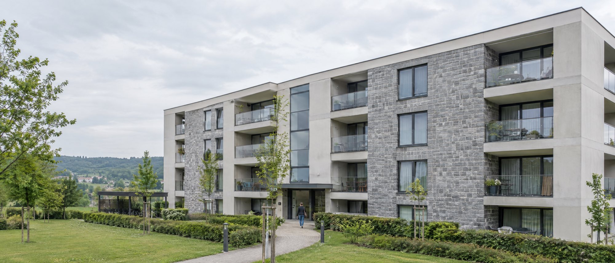 Appartementsgebouw in steen en beton, met gemeenschappelijke tuin en pad naar de ingang